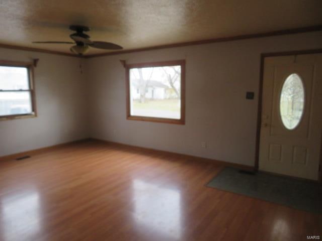 foyer featuring ceiling fan, light wood-type flooring, and a textured ceiling