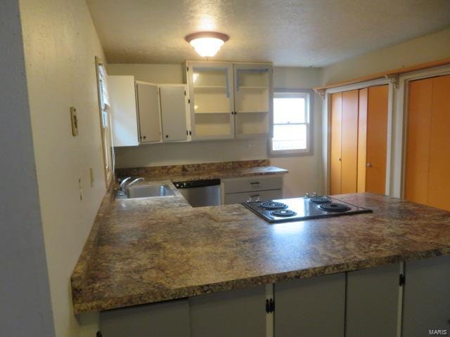 kitchen featuring sink, stainless steel appliances, kitchen peninsula, dark stone countertops, and white cabinets