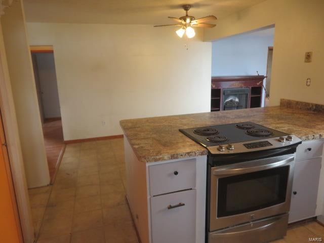 kitchen with kitchen peninsula, white cabinetry, ceiling fan, and stainless steel electric range