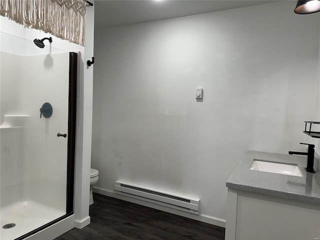 bathroom featuring walk in shower, baseboard heating, hardwood / wood-style floors, toilet, and vanity