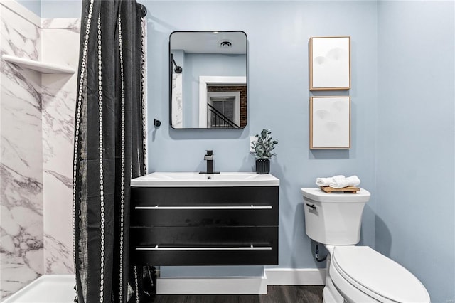 bathroom featuring a tile shower, toilet, vanity, and hardwood / wood-style flooring