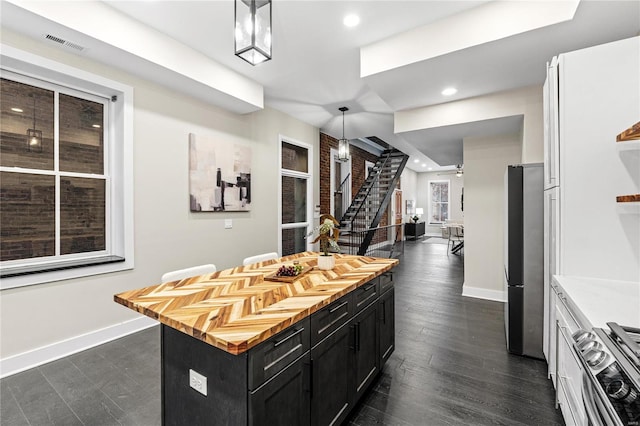 kitchen featuring pendant lighting, white cabinets, dark hardwood / wood-style floors, appliances with stainless steel finishes, and a kitchen island