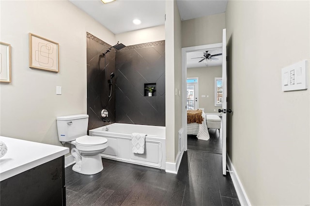 full bathroom with vanity, tiled shower / bath combo, ceiling fan, wood-type flooring, and toilet