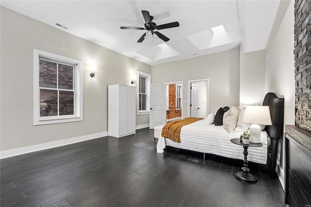 bedroom featuring a skylight, ceiling fan, and dark wood-type flooring