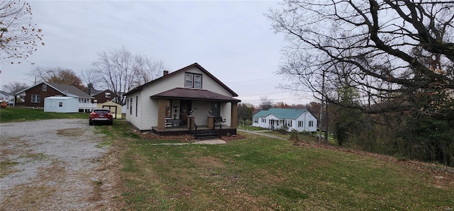 bungalow featuring covered porch, an outbuilding, a garage, and a front lawn