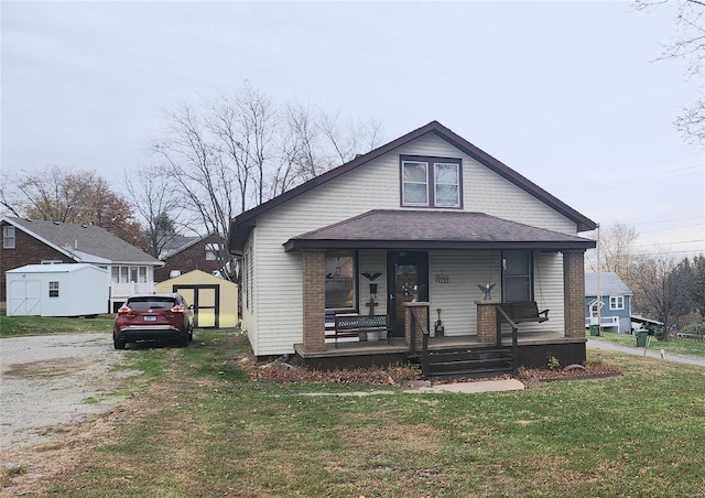 bungalow-style home with a storage unit, a porch, and a front lawn