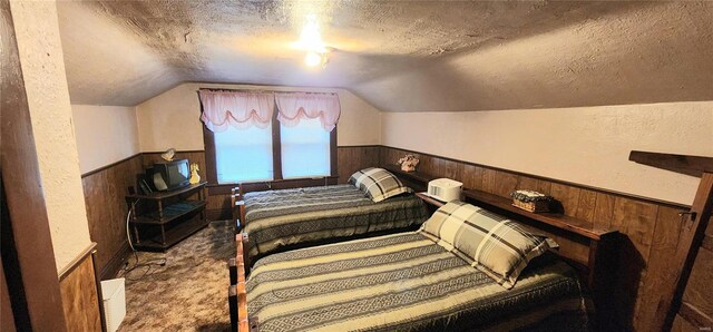 carpeted bedroom with a textured ceiling, wooden walls, and lofted ceiling