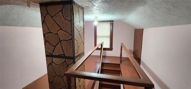 stairway with a textured ceiling and lofted ceiling