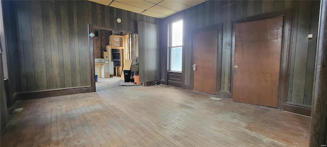 empty room featuring light wood-type flooring and wooden walls