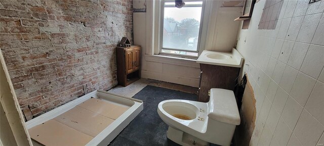 bathroom featuring brick wall and toilet