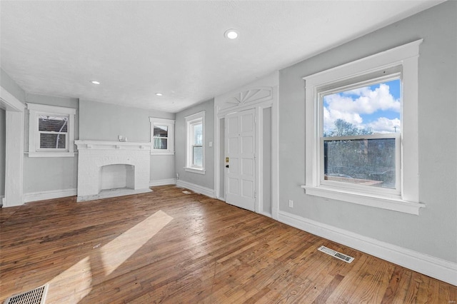 unfurnished living room with hardwood / wood-style floors and a brick fireplace