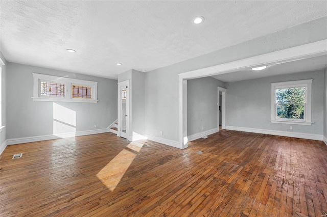 spare room with a textured ceiling and dark hardwood / wood-style floors