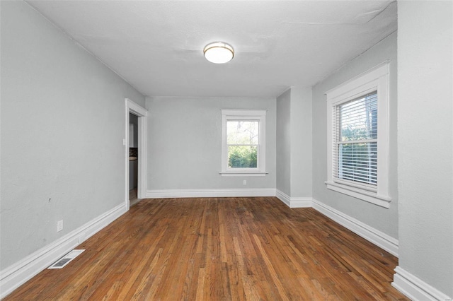 unfurnished room featuring a healthy amount of sunlight and dark wood-type flooring