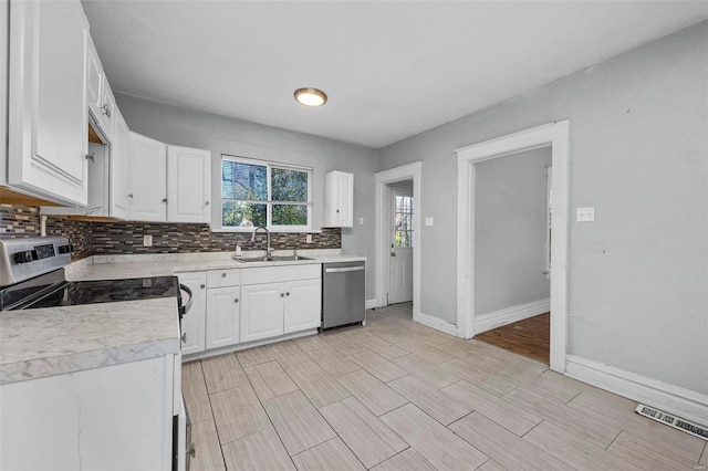 kitchen featuring appliances with stainless steel finishes, light hardwood / wood-style floors, white cabinetry, and sink