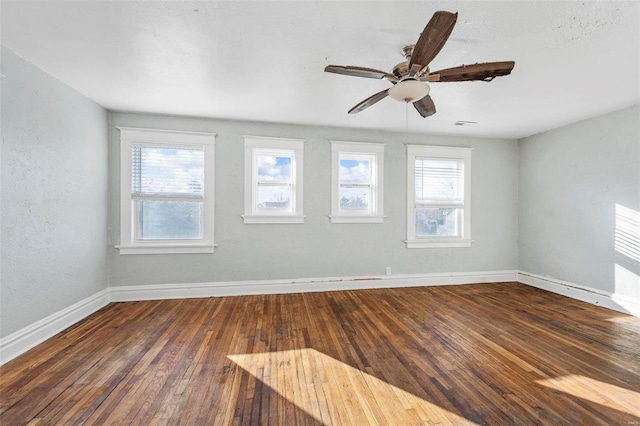 empty room featuring a wealth of natural light, ceiling fan, and dark hardwood / wood-style floors