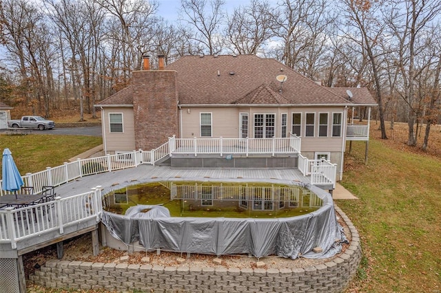 rear view of property with a wooden deck and a yard