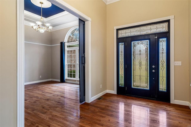 foyer entrance with a tray ceiling, crown molding, dark hardwood / wood-style floors, and a notable chandelier