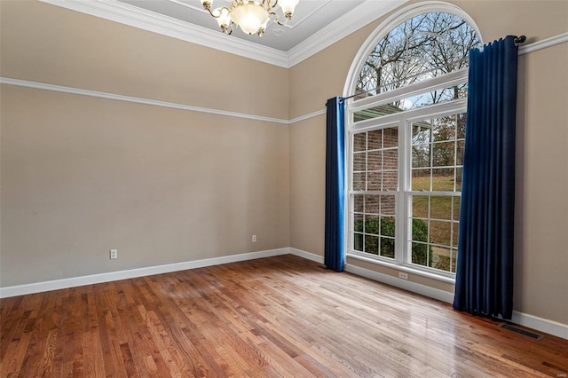 unfurnished room with hardwood / wood-style flooring, an inviting chandelier, and ornamental molding