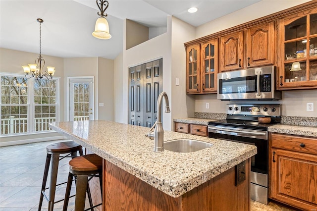 kitchen featuring a center island with sink, sink, light stone countertops, a notable chandelier, and stainless steel appliances