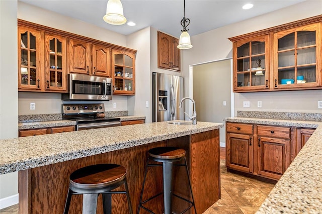 kitchen featuring stainless steel appliances, hanging light fixtures, a breakfast bar area, and sink