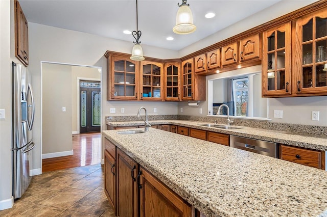 kitchen featuring light stone counters, sink, hanging light fixtures, and appliances with stainless steel finishes