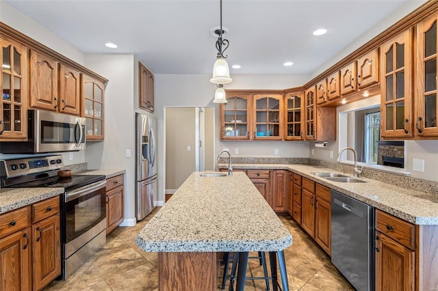 kitchen with pendant lighting, sink, stainless steel appliances, and a kitchen island with sink