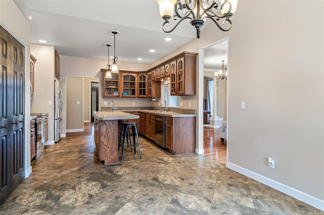 kitchen featuring appliances with stainless steel finishes, a kitchen breakfast bar, pendant lighting, a notable chandelier, and an island with sink