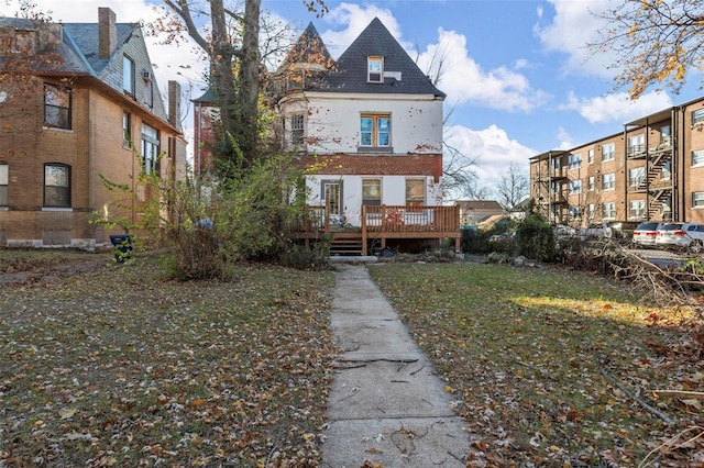 back of property with a deck and a lawn