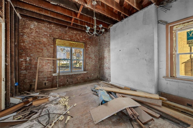 miscellaneous room featuring an inviting chandelier and brick wall