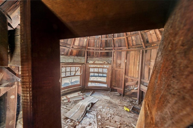 miscellaneous room featuring lofted ceiling and wood walls