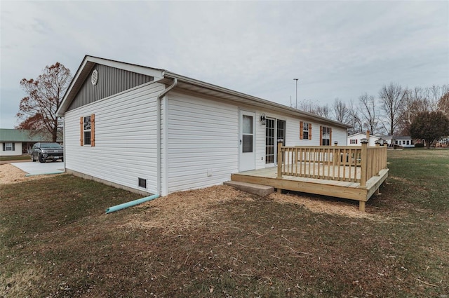 rear view of house featuring a wooden deck and a yard