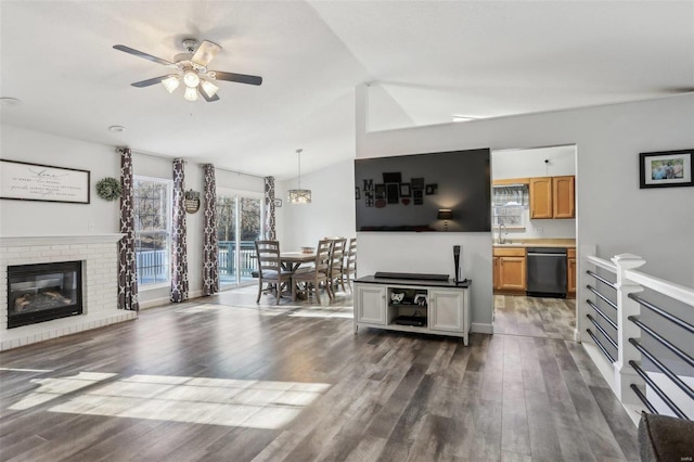 living room with lofted ceiling, ceiling fan, a brick fireplace, and dark hardwood / wood-style flooring