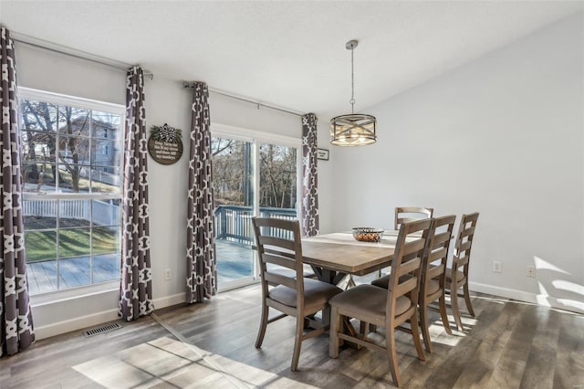 dining area featuring an inviting chandelier, lofted ceiling, and hardwood / wood-style flooring