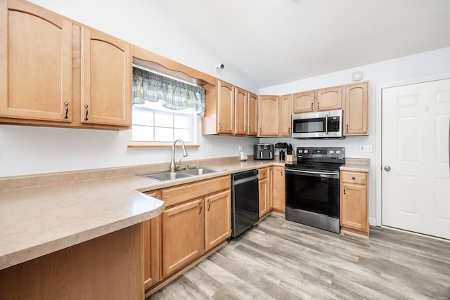 kitchen with light hardwood / wood-style floors, appliances with stainless steel finishes, light brown cabinetry, vaulted ceiling, and sink