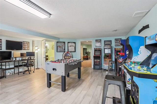 game room with a textured ceiling and light hardwood / wood-style flooring