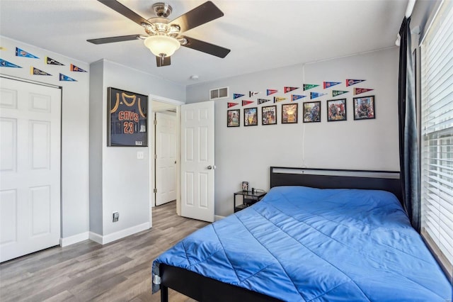 bedroom featuring ceiling fan, wood-type flooring, and multiple windows