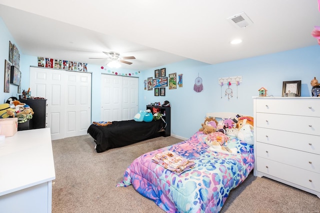 carpeted bedroom with ceiling fan and two closets