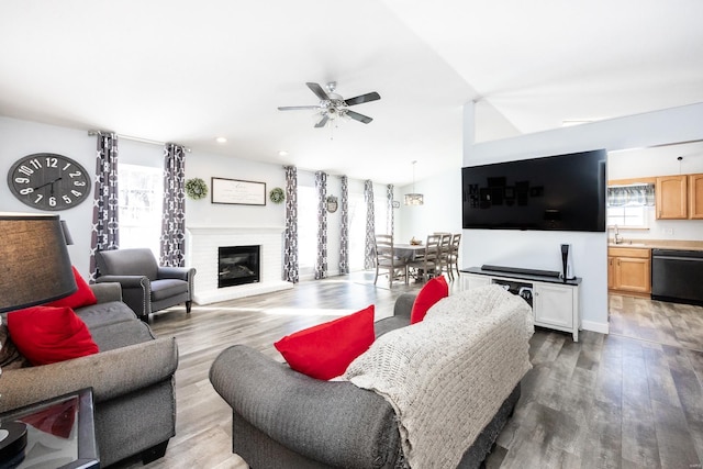 living room featuring ceiling fan, wood-type flooring, and a fireplace