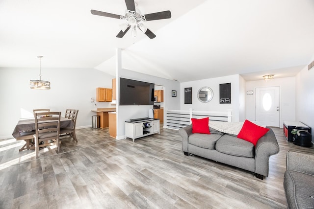 living room with vaulted ceiling, ceiling fan, and light wood-type flooring