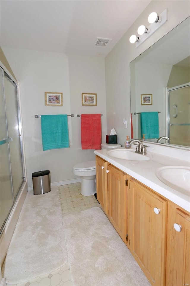 bathroom with a shower with door, vanity, and toilet