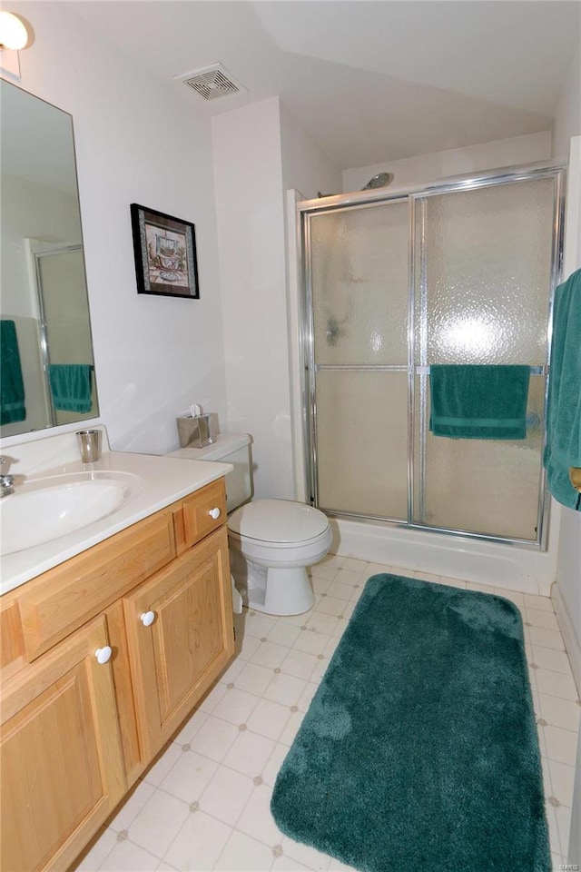 bathroom featuring tile patterned flooring, vanity, toilet, and a shower with shower door