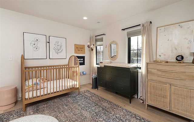 bedroom with a nursery area and hardwood / wood-style flooring