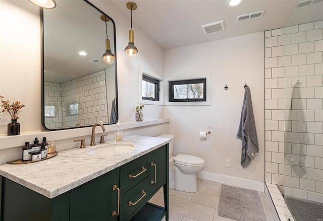 bathroom featuring tiled shower, vanity, tile patterned floors, and toilet