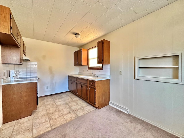 kitchen with sink, stainless steel electric range oven, backsplash, and light carpet