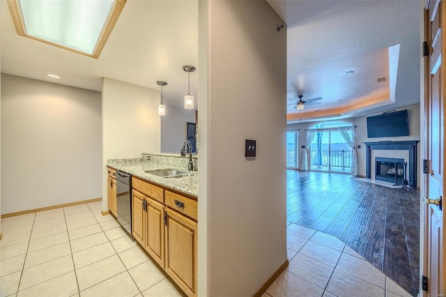 kitchen with ceiling fan, sink, black dishwasher, light stone counters, and light hardwood / wood-style flooring