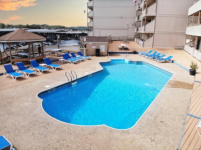 pool at dusk with a gazebo and a patio area