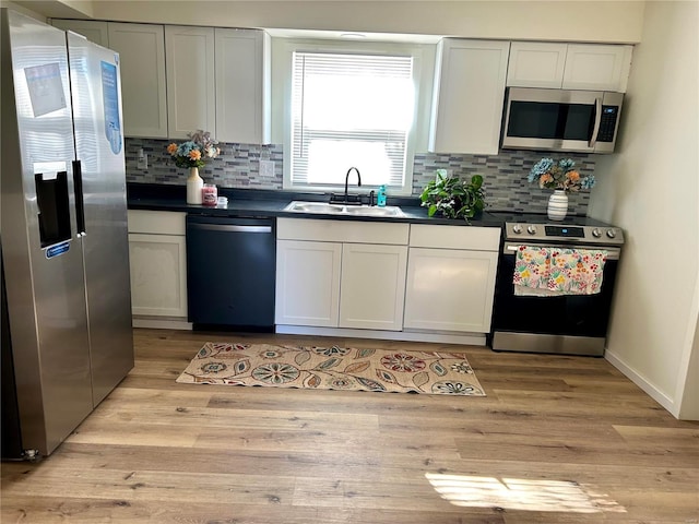 kitchen with sink, stainless steel appliances, light hardwood / wood-style floors, and white cabinets