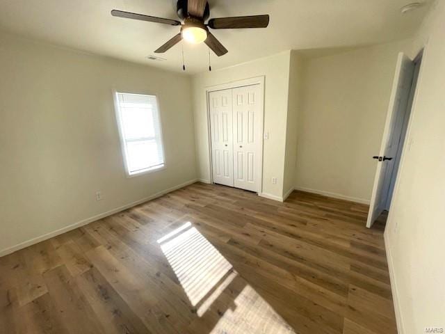 unfurnished bedroom featuring dark hardwood / wood-style flooring, ceiling fan, and a closet