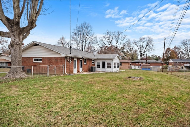 back of property with central AC unit and a yard