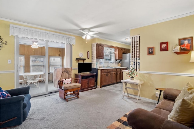 carpeted living room with crown molding, sink, and ceiling fan